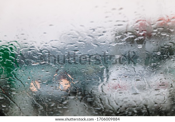 Traffic stands still, on a cold, wet day,\
shot through a windscreen, focusing on the rain droplets, tailights\
out of focus. View from car glass window. Conceptual bad weather\
background.