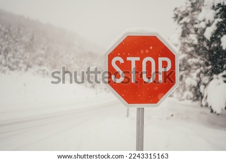 Traffic stop sign over snowy winter scene. Warning sign for transportation regulation. Winter mountain landscape. Car driving on ice and snow.