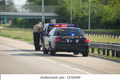 Traffic Ticket Police Vehicle - A Police Cruiser With The Lights Flashing Has Stopped A Speeding Car Along The Interstate Highway And Is Issuing A Ticket.