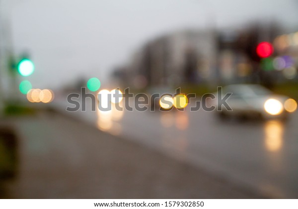 Traffic traffic in\
the town. Green traffic light. Cars go on the road. Blurred image.\
Wet road after rain.