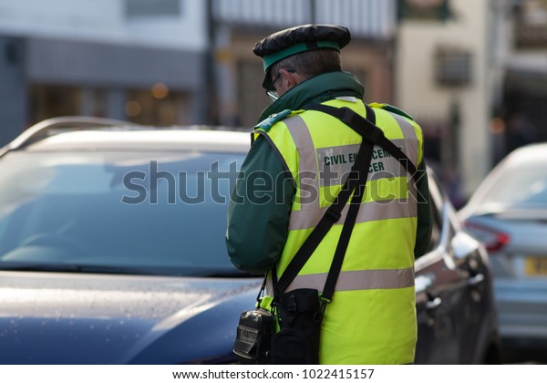 traffic warden\
civil enforcement officer wearing reflective yellow vest issuing\
fixed penalty parking ticket\
fine