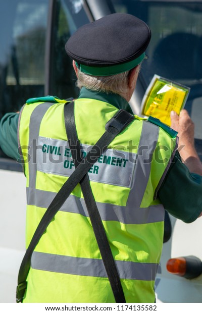 traffic warden civil enforcement officer wearing
reflective yellow vest issuing fixed penalty parking ticket fine to
white van