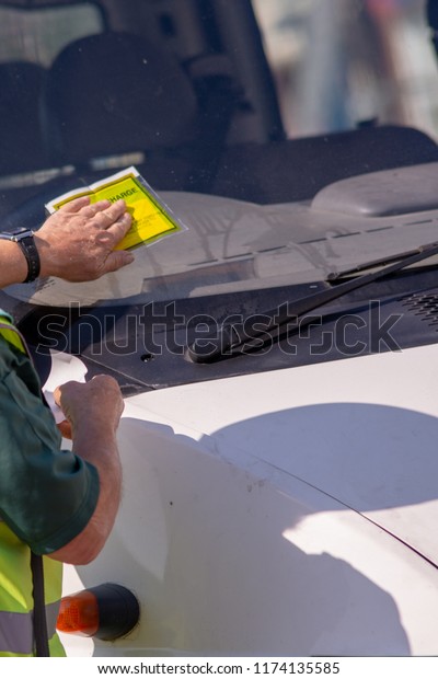 traffic warden civil enforcement officer wearing\
reflective yellow vest issuing fixed penalty parking ticket fine to\
white van