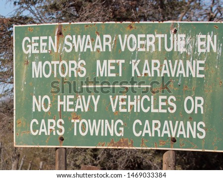 
traffic warning text sign in two languages Afrikaans and English, indicating not to use heavy traffic on secondary gravel road