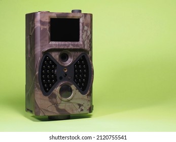 Trail Camera On A Green Background. Photo And Video Trap. Animal And Surroundings Monitoring Device With Motion Sensor And Night Vision