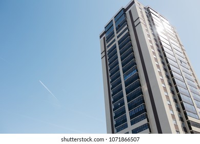 Trail From The Flying Aircraft In The Clear Sky On The Background Of A House With Colored Windows