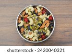 Trail mix nuts and seeds in a plate on wooden background top view 