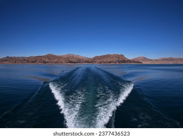 Trail on water surface behind of motor boat on lake Titicaca, Peru