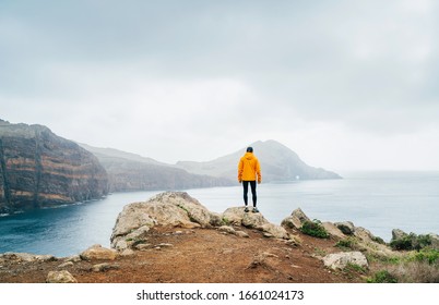 Trail runner man dressed orange waterproof jacket, running tights and shoes enjoying Atlantic ocean bay view on Ponta de Sao Lourenço peninsula -the easternmost point of Madeira island, Portugal - Powered by Shutterstock