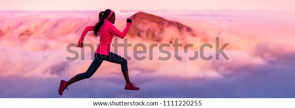Trail runner nature landscape banner of running\
woman sports athlete on mountains background panorama crop in cold\
weather with pink clouds at sunset. Amazing scenic view of peaks in\
altitude.