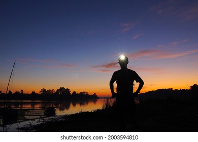 A trail runner standing with a headlamp on his head with silhouette sky - Shutterstock ID 2003594810