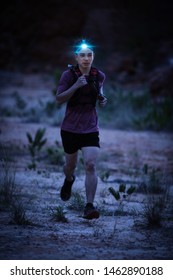 Trail Runner Wearing Headlamp Running On The Rocky Road In The Night