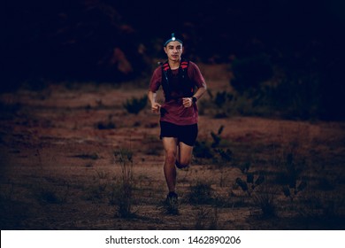 Trail Runner Wearing Headlamp Running On The Rocky Road In The Night