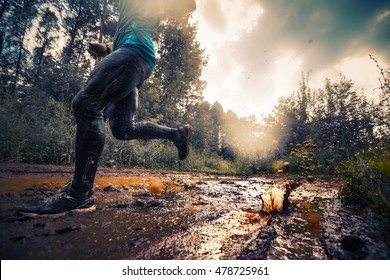 Trail running athlete moving through the dirty puddle in the rural road - Shutterstock ID 478725961