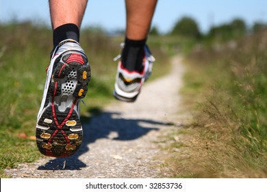 Trail running. Freeze action closeup of running shoes in action. Shallow depth of field, focus on left shoe.