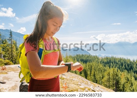 Trail running. Trail runner looking at smartwatch sports watch for GPS data and heart rate app. Runner woman running cross-country trail run training hiking outside in mountains.