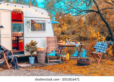 trailer of mobile home or recreational vehicle stands on shore of pond in camping in autumn near table set, concept of family local travel in native country on caravan or camper van and camping life - Shutterstock ID 2051816471