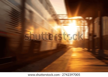 A train is blurred with motion at a station platform as the sun sets, casting a warm glow.