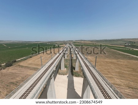 Train bridge over a green field, countryside, from drone's eye