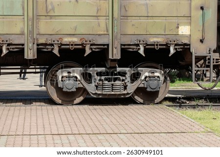 A train car with rusted metal on the front. The train is parked on a brick walkway