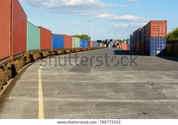 A
train of cargo containers parked in a shipping
yard.