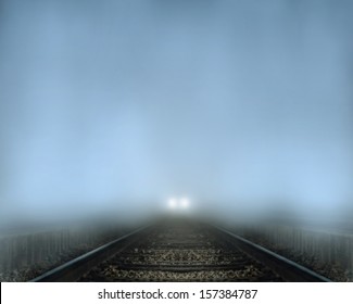 A Train Coming Down Tracks At Night In The Fog