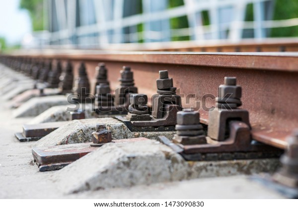 Train comming. Railway track. Railway sleepers\
and rails close-up. Iron bolts and connections. Railway background.\
Railway crossing.