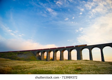 Train crosses the famous Ribblehead Viaduct. The Ribblehead Viaduct or Batty Moss Viaduct carries the Settle–Carlisle Railway across Batty Moss in the valley of the River Ribble at Ribblehead. - Shutterstock ID 713989372