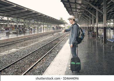 Train Delay. Young Asian Man Looking In His Watch While Waiting Train At Station.(color Toned Image)