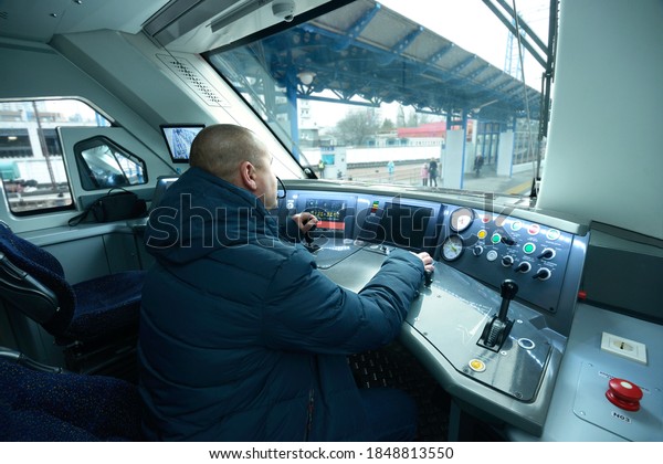 Train driver sitting in the cabin of\
locomotive of passenger train in front of dashboard putting hand on\
the start lever. December 22, 2019. Kiev,\
Ukraine