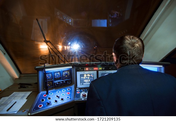 Train driver in the tunnel. Rear view.\
Profile of the person driving the train. Light at the end of\
railway tunnel. Sensors, buttons, arrows, control panel. Cockpit,\
crew, railway worker,\
construction