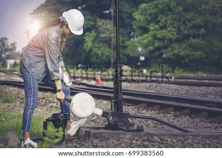 Train engineers beautiful girl wearing jeans and a white helmet're using switch rails and rail inspection system used for travel by train.