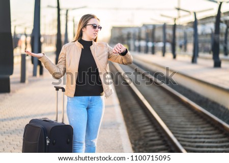 Train late, delayed, canceled or behind schedule. Confused woman looking at the time and watch while waiting in platform.  Unhappy person spreading hands.