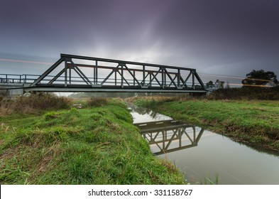 Train lights on railway steel truss bridge in Poland, over small river