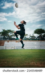 Train Like A Pro. Full Length Shot Of A Handsome Young Rugby Player Catching A Ball Mid-air On The Field.