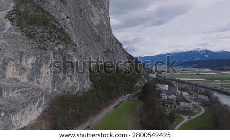 A train moves along tracks through a rocky mountain area with distant peaks.