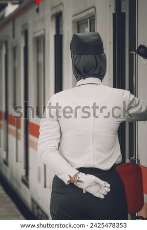 Train officer standing beside train while train stop at the train station