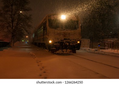 Train On The Railway In Heavy Snow Storm At Night. Passenger Train Moves On The Railway In Winter In Ukraine.