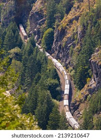 Train Passes Through A Mountain. Freight Train On A Railway Line On A Mountain Pass. Train Passing Through The Woods, Aerial View. Cargo Train With Fuel Passing Through The Forest Top View, Nobody