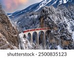 Train passes through snow-capped mountains in Filisur, Switzerland in the winter of the Swiss Alps.