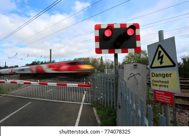 Train passing Red lights at an unmanned Level crossing, East Coast Main Line Railway, Peterborough, Cambridgeshire, England, UK