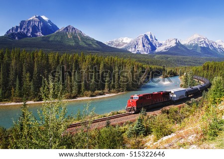 Train passing through Bow valley under the surveillance of mighty Rocky Mountains.