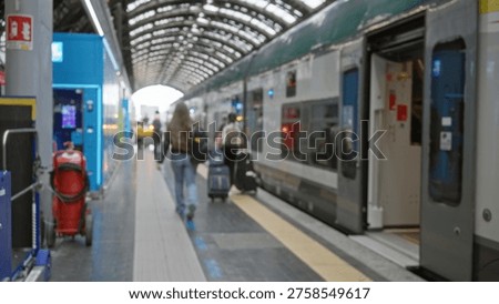 Train platform defocused background with soft bokeh, blurred luggage and open carriage under arched roof; background copyspace backplate calm.