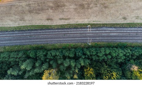 Train Railroad Tracs Next To A Forest And Field. Top Aerial View Of German Train System Near Munich