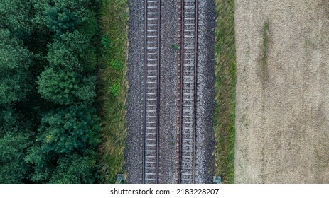 Train Railroad Tracs Next To A Forest And Field. Top Aerial View Of German Train System Near Munich