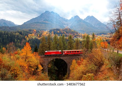 Ein Zug der Rhätischen Eisenbahn auf einer Brücke durch Herbstfarben
