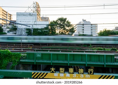 A train runs over an elevated bridge.(translation: 大型車徐行 means Large vehicles have to drive slowly in japanese, 制限高 means limited of height in jananese)