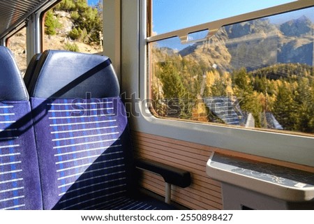 train seats with a table for drinks and with panoramic windows, behind which the landscape of the Alps in Switzerland and a beautiful forest, photos during the train movement