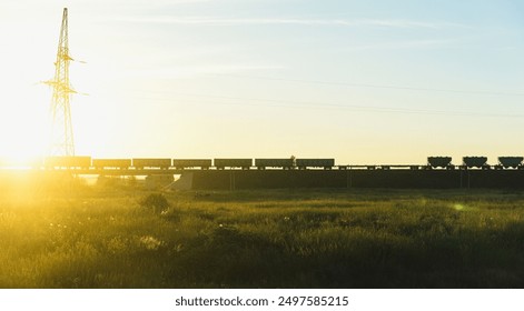 Train silhouette into the sun background, shadow, sunlight, field, light blue sky, electric tower - Powered by Shutterstock