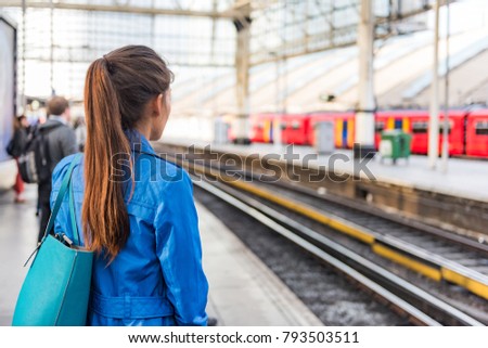 Train station morning commute woman going to work waiting for train to arrive. People on public transport platform . Commuting on rush hour. View of businesspeople and rails city lifestyle.